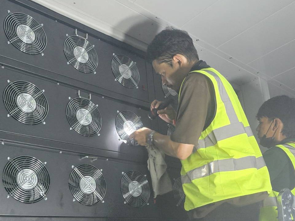 Wiping down the fan bank of an air-conditioning unit in a systems room